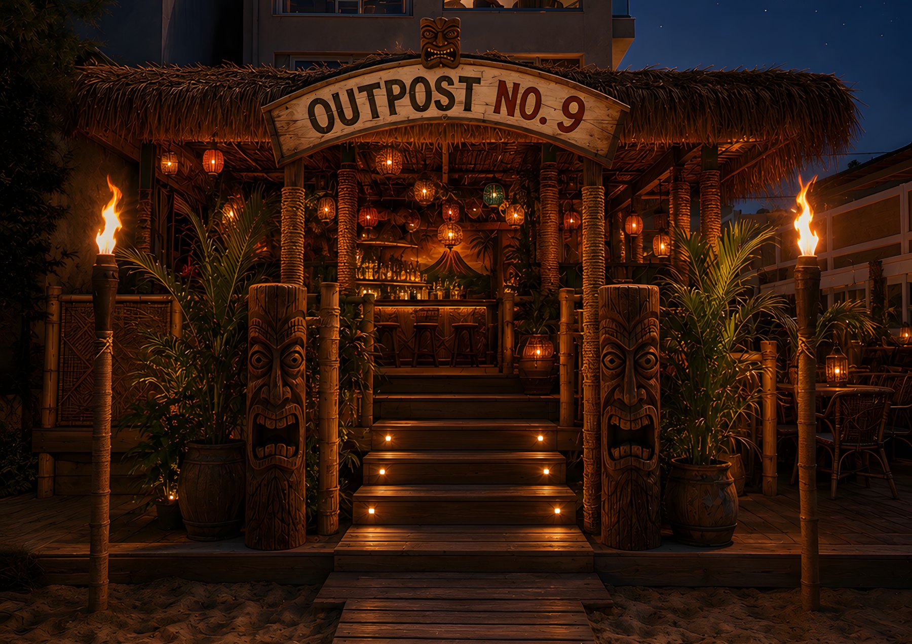 The Outpost No. 9 beachfront entrance at night: thatched roof, the sign, tiki torches, and totems flanking the steps up to the lit bar